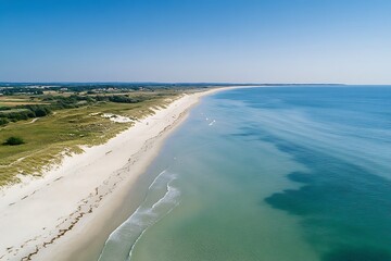 Wall Mural - Aerial view of a serene beach with clear waters and sandy shores under a blue sky.