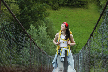 Poster - Young hiker walking on bridge in mountains