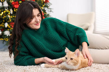 Poster - Woman with cute ginger cat lying on rug in room decorated for Christmas