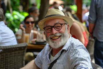 Poster - Portrait of a senior man in a hat and glasses sitting in a cafe and smiling.