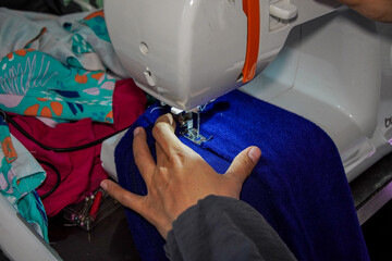 A close-up view of a hand guiding fabric under a sewing machine needle, showcasing the process of sewing. Sewing Machine in Action