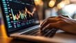© maesarin - Close up view of hands typing on a laptop computer with financial graphs charts and diagrams displayed on the screen showcasing the concept of data analysis investment and business strategy