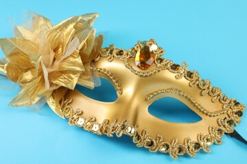 Poster - One golden carnival mask on light blue background, closeup