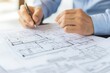© ImagePulse - Engineers holding building specifications and adjusting details on floor plans, close-up of hands and documents