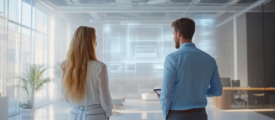 Wall Mural - a man and a woman stand facing a holographic screen in a modern office, looking at a digital design 