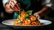 © ธนากร บัวพรหม - A chef delicately garnishing a plate of shrimp pasta with fresh basil, showcasing culinary artistry and vibrant flavors.