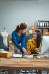 two asian business woman work at desk, selling fashion clothes online. they are packing checking ite