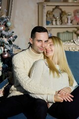 A beautiful young married couple in a room decorated for the new year or Christmas. The atmosphere of the holiday.