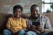 © Rahul - Addicted of gadgets african dad and son sitting on couch, Generative AI