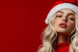© Vesovic  - A stunning woman in a Santa hat against a red background, embodying holiday spirit and style with a bold and festive appearance.