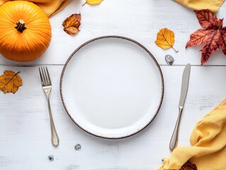 Autumn tablescape with pumpkin decor on a white wooden surface featuring an empty plate cutlery yellow linen napkin and dried leaves for a festive atmosphere