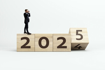 Businessman waiting for 2025 year loading on wooden blocks. White background. New Year, annual report concept.