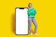 © deagreez - Full length photo of cheerful pretty lady dressed green sweatshirt arfms crossed typing modern gadget empty space isolated yellow color background