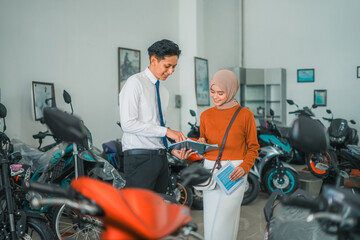 motorcycle sales man chats with a veiled female visitor at a motorcycle showroom