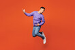© ViDi Studio - Full body side view young happy man of African American ethnicity he wear purple sweatshirt casual clothes jump high play air guitar isolated on plain red orange background studio. Lifestyle concept.