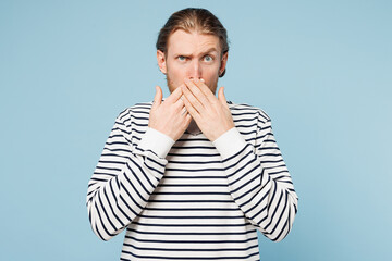 Poster - Young sad shocked surprised unhappy man he wear striped sweatshirt casual clothes look camera put hand on mouth isolated on plain pastel light blue cyan background studio portrait. Lifestyle concept.