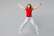 © ViDi Studio - Full body young smiling excited happy woman she wear red t-shirt casual clothes jump high look camera with outstretched hands legs isolated on plain grey background studio portrait. Lifestyle concept.