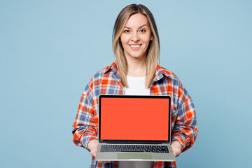 Wall Mural - Young IT woman she wears red shirt t-shirt casual clothes hold use work on laptop pc computer with blank screen workspace area isolated on plain pastel light blue cyan background. Lifestyle concept.