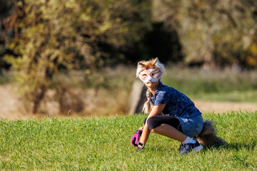 Cute young little kid girl wear cat furry mask enjoy have fun playing outdoors in forest street park. Children therian wild animal character trendy fan culture. Teenager social expression hobby