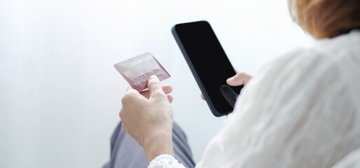 Asian girl shopping online holding credit and using smartphone enter their card number in the mobile phone app to purchase and payment in internet store