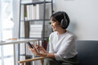 © Wasana - Young asian woman listening music with headphones and using smartphone at home
