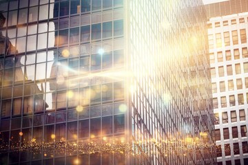 Sticker - A close-up of a modern glass building with a slightly blurred background. The sun shines brightly, reflecting off the windows, creating a bokeh effect.