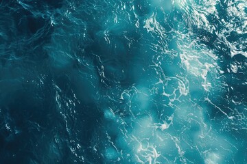 A topdown view of turquoise ocean water with white foam.