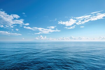 Calm blue ocean with a clear sky and fluffy white clouds.