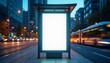 © natakot - An empty bus stop with a blank billboard illuminated by surrounding city lights in the evening. The scene captures an urban setting with a focus on advertising and city life.