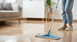 © Tati - Person mopping clean wooden floor in tidy living room with plant