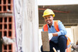© Robert Kneschke - Full length portrait of happy young female labor with trowel crouching on plank by wall at construction site