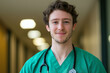 © Rohit k  - Young man training to be a doctor exudes happiness and optimism in a bustling hospital hallway, reflecting his dedication to healthcare and embodying the future of medicine