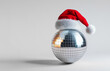 © Shootdiem - Silver disco ball wearing a santa hat is standing on a white background for a christmas party invitation