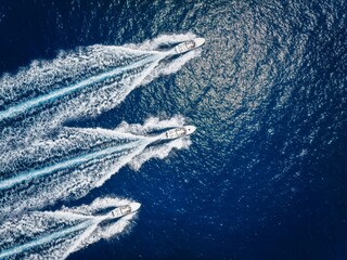 Wall Mural - aerial top down view of three motorboats racing over the ocean with high speed