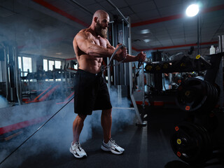 Wall Mural - Bald Caucasian bodybuilder training chest using cable crossover in gym. 