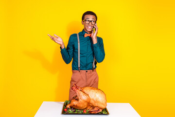 Wall Mural - Portrait of elegant young man talk phone roasted thanksgiving day turkey isolated on yellow color background