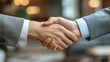 © Suchanon - Close-up handshake between two people in formal attire, representing agreement and partnership.