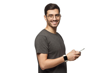 Young man standing, holding smartphone, looking at camera and smiling nicely