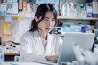 © larrui - Focused Female Scientist Working on Laptop in a Busy Research Laboratory