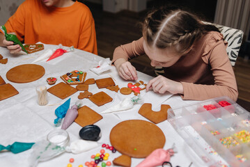 Little girl adding colorful candy on a gingerbread house she is decorating 