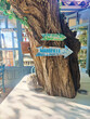Carteles colgados en un árbol que señalan la dirección hasta Cadaqués y Marsella