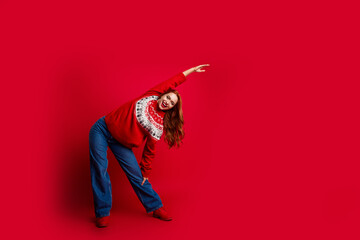 Canvas Print - Photo portait of sportive girl wearing traditional seasonal ugly sweater new year holiday stretching isolated on red color background