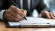© JP STUDIO LAB - Hand of a businessperson signing a document with a pen, dark wood desk in background, close-up shot, business transaction and agreement concept