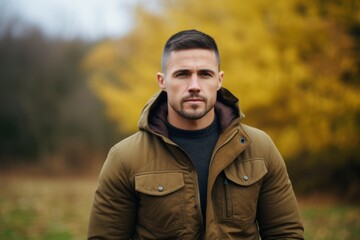 Portrait of a handsome young man in a warm jacket in the autumn park.