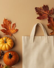 Wall Mural - Autumn tote bag mockup flatlay on tan background featuring autumn leaves and pumpkins with ample negative space