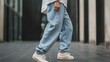 © prime stock - A person wearing light blue jeans and white sneakers walks on a city street.