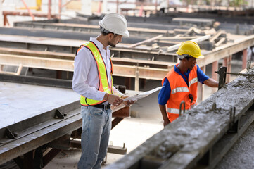 Engininspecting the work that technicians are doing by pouring cement for building components and houses.