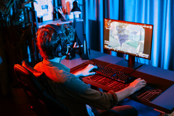 Host channel of young gaming streamer, team gamer playing battle game shooting with multiplayer at warship on pc screen with back side image, wearing headset with mic at digital neon room. Gusher.