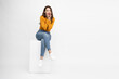 © comzeal - Young Asian woman sitting on white box and open mouths raising hands screaming announcement isolated on white background