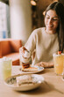 © BGStock72 - A joyful moment at a cozy cafe as a woman pours syrup over a slice of cheesecake, capturing the essence of indulgence and relaxation